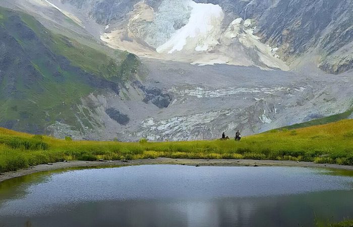 lake in front of shkhara glacier with two horseriders