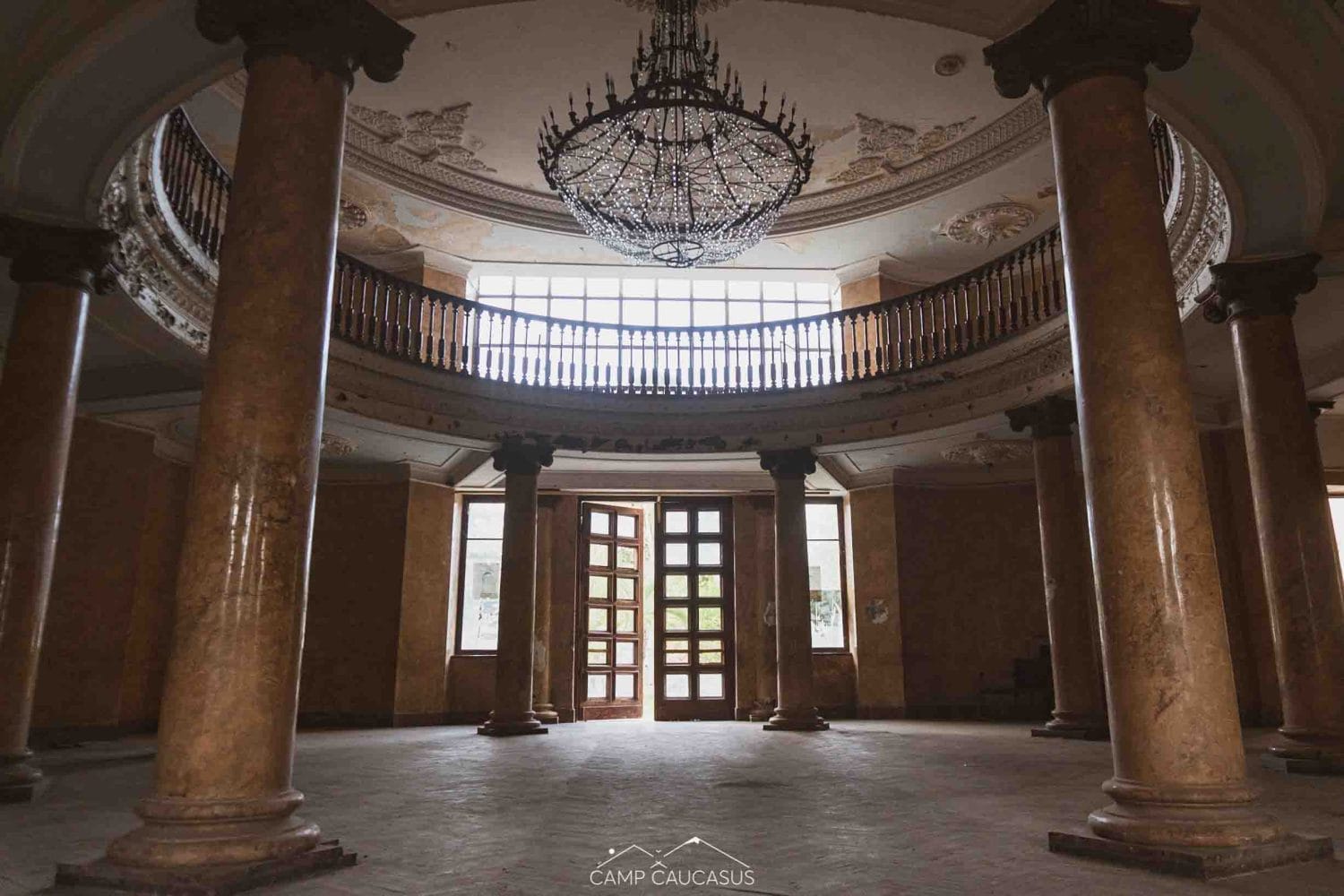 Interior of abandoned Tskaltubo sanatorium with neoclassical columns, chandelier, and Stalin-era Soviet architecture