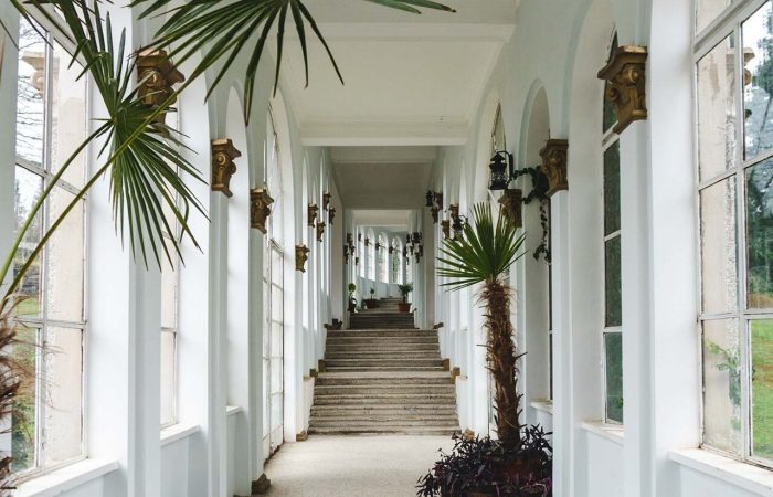 White corridor adorned with flowers inside an abandoned Soviet-era sanatorium in Tskaltubo, Georgia, showcasing elegant architectural elements and the haunting beauty of forgotten spaces