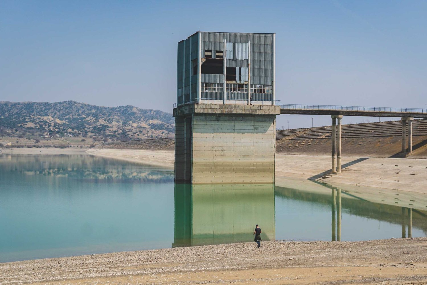 Person walking near Dali Mountain reservoir water control tower at Vashlovani reservoir, Georgia