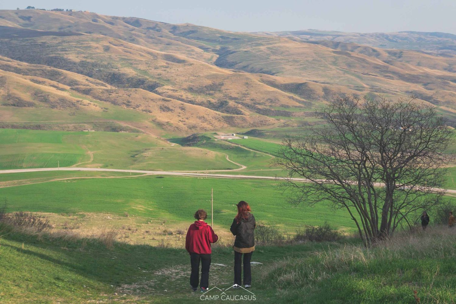 Hikers walking through green pastures in Kakheti region at Vashlovani National Park, Georgia