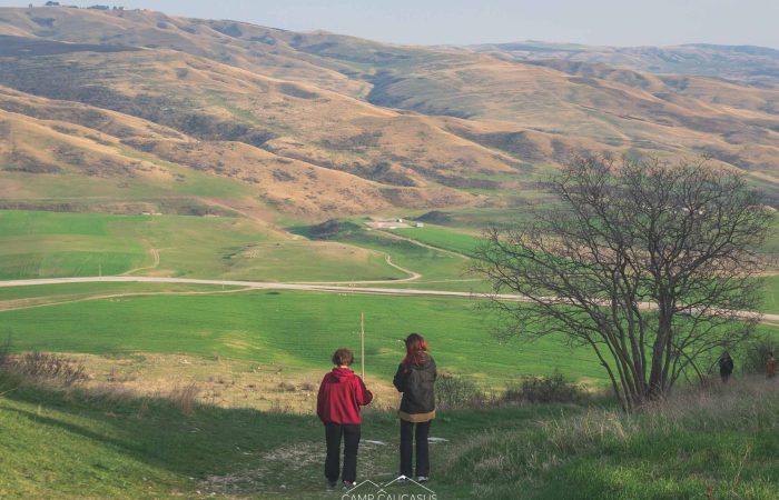 Hikers walking through green pastures in Kakheti region at Vashlovani National Park, Georgia