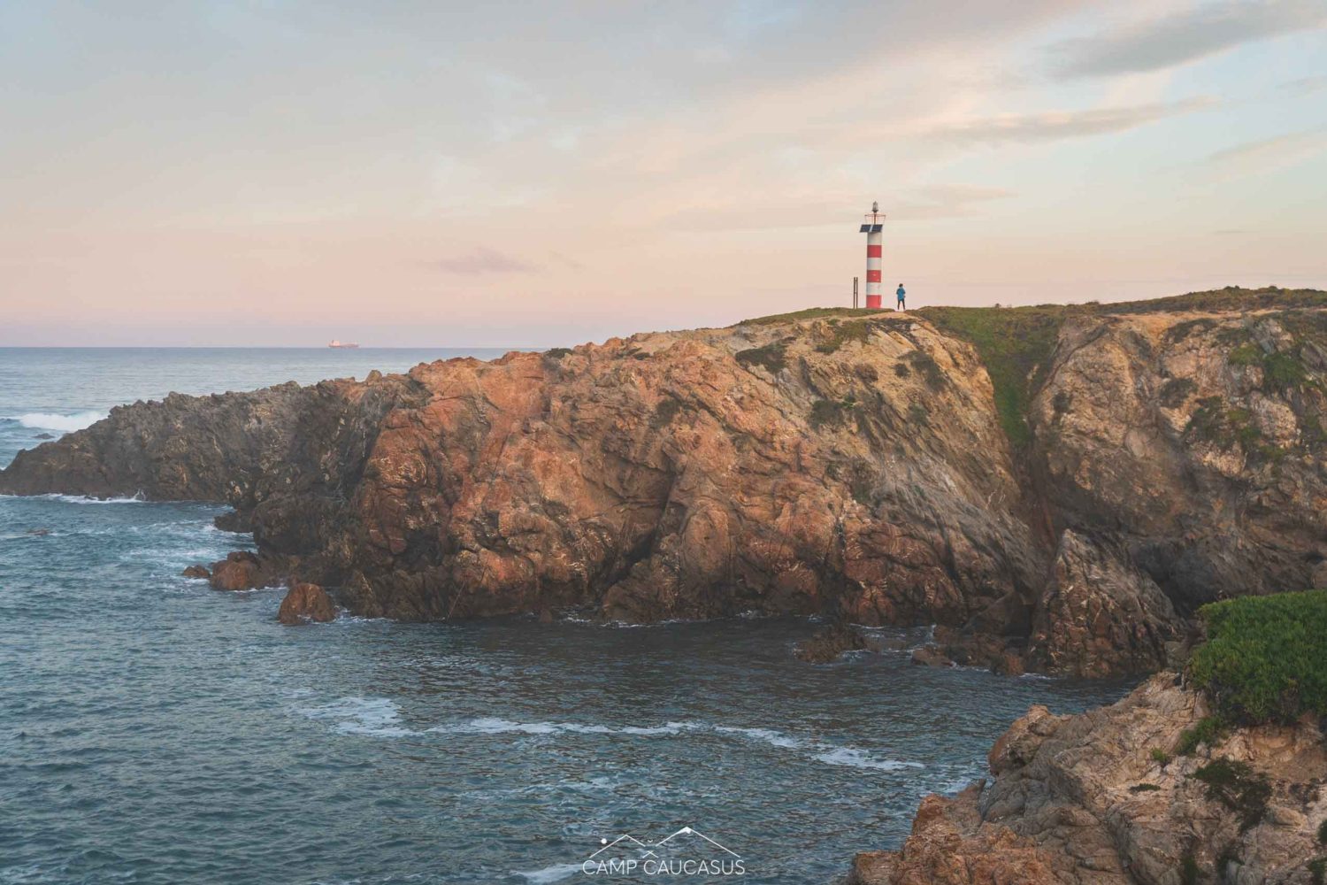 Sunset over cliffs and lighthouse on the Fisherman’s Trail near Porto Covo, Portugal.
