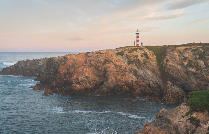 Sunset over cliffs and lighthouse on the Fisherman’s Trail near Porto Covo, Portugal.