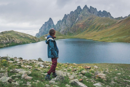 A hiker enjoying the view of the breathtaking Abudelauri Lake with dramatic peaks in the background during a Camp Caucasus trekking tour in Georgia.